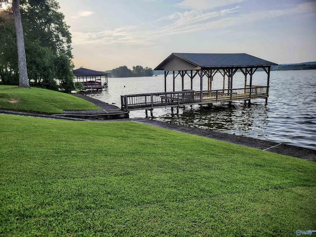 view of dock with a yard and a water view