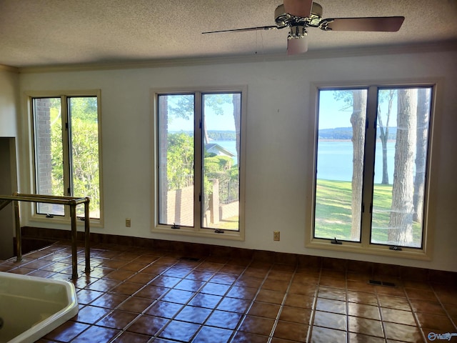 empty room featuring a water view, a wealth of natural light, and a textured ceiling