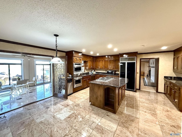 kitchen featuring black appliances, a kitchen island, dark stone counters, hanging light fixtures, and ceiling fan