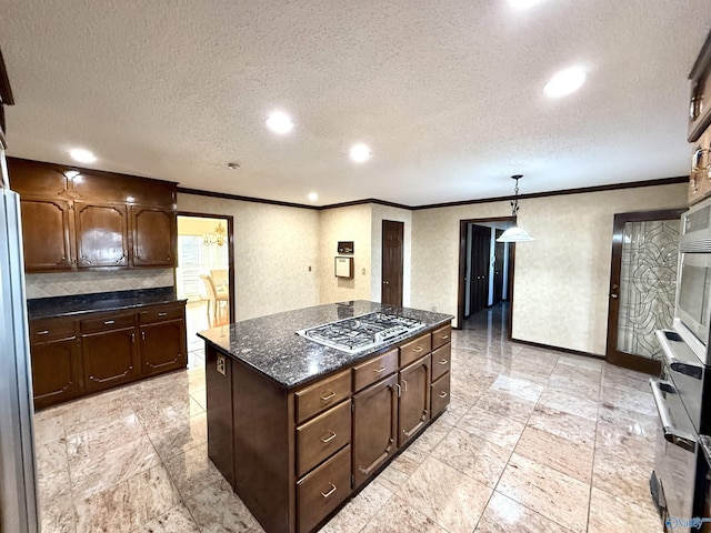 kitchen with a textured ceiling, dark brown cabinetry, a center island, decorative light fixtures, and stainless steel gas cooktop