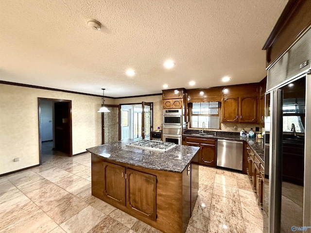 kitchen with appliances with stainless steel finishes, a center island, decorative light fixtures, ornamental molding, and sink