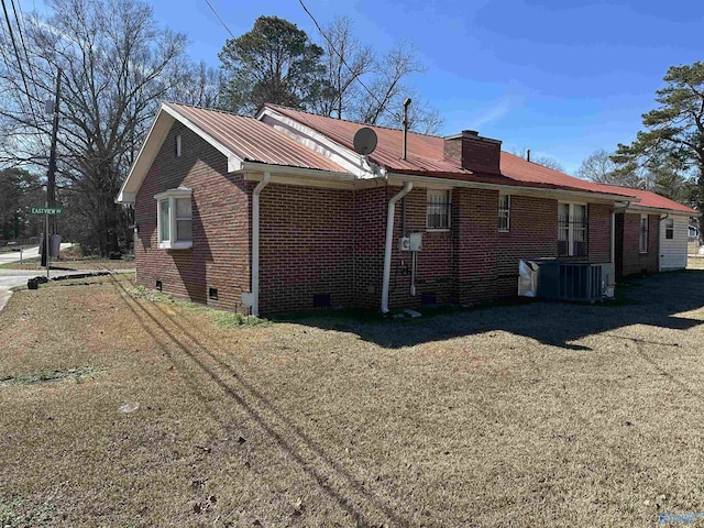 view of side of home featuring a chimney, metal roof, crawl space, cooling unit, and brick siding