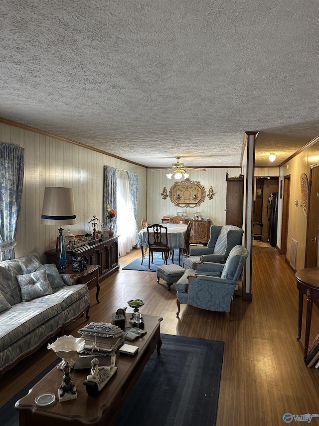 living area with ornamental molding, a textured ceiling, and wood finished floors