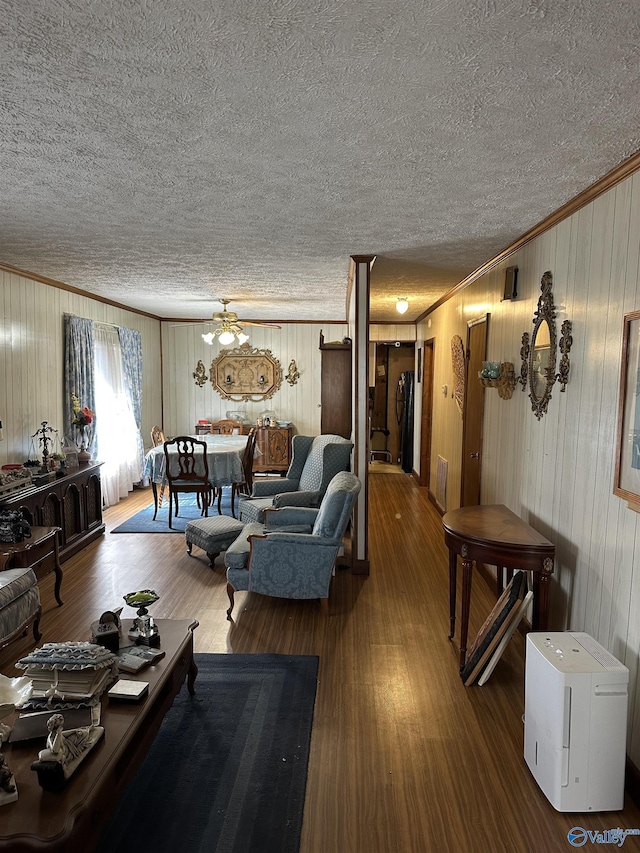 living area with crown molding, a textured ceiling, visible vents, and wood finished floors