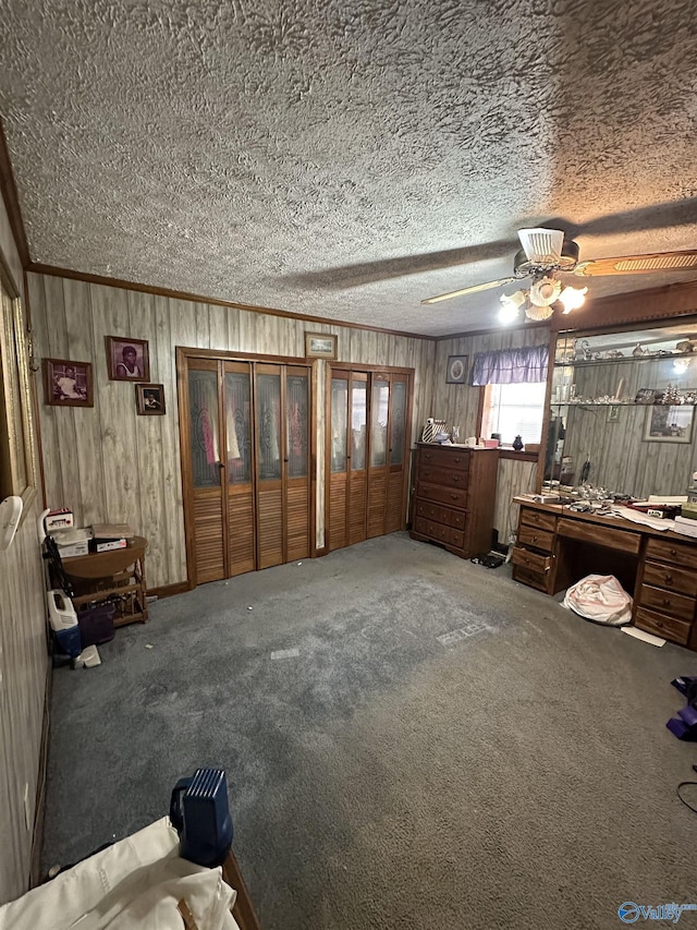 unfurnished bedroom featuring a textured ceiling, ceiling fan, ornamental molding, and carpet flooring