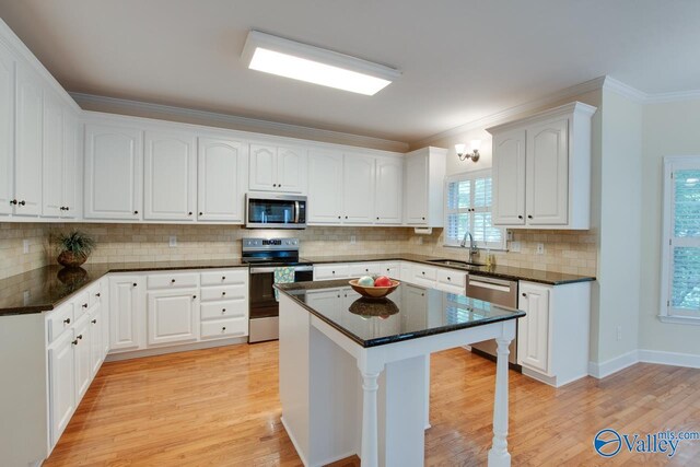 102 Twin Island Cir, Madison, AL 35758 - kitchen with appliances with stainless steel finishes, a sink, light wood-style flooring, a kitchen breakfast bar, and white cabinetry