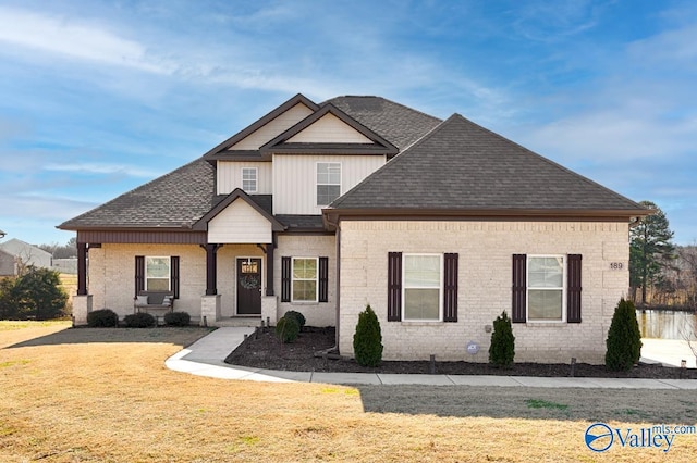 view of front of property featuring roof with shingles, a front lawn, and brick siding