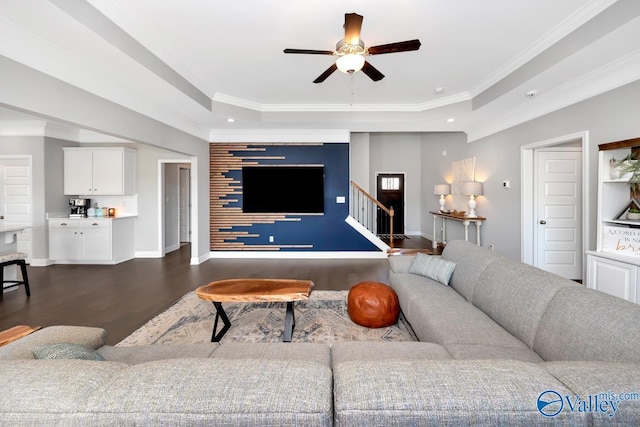 living area with an accent wall, dark wood-type flooring, baseboards, stairway, and a tray ceiling