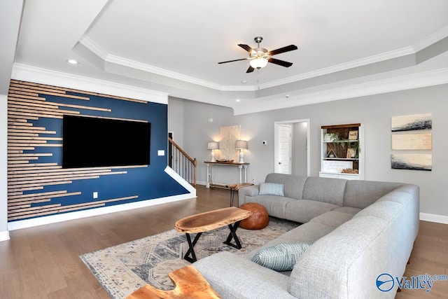 living area with baseboards, stairway, a raised ceiling, and wood finished floors