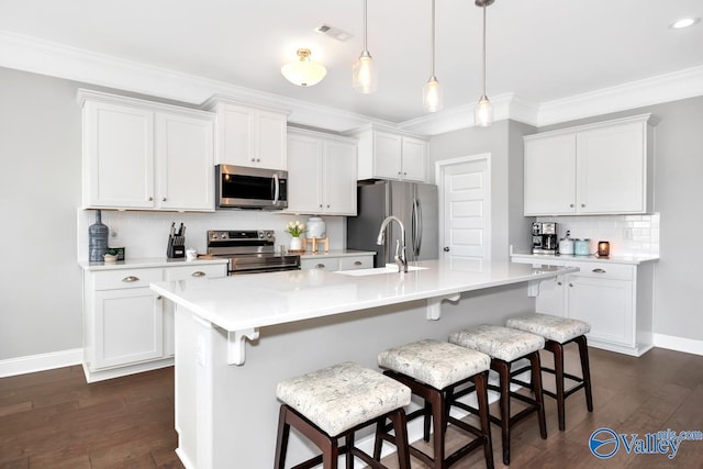 kitchen featuring stainless steel appliances, a breakfast bar area, light countertops, and white cabinets