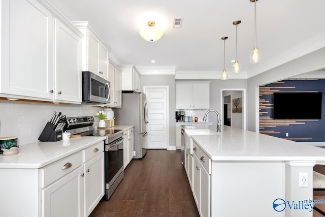 kitchen featuring hanging light fixtures, white cabinetry, a kitchen island with sink, and appliances with stainless steel finishes