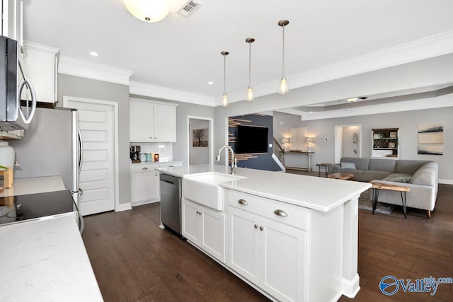 kitchen featuring visible vents, white cabinets, an island with sink, stainless steel appliances, and pendant lighting