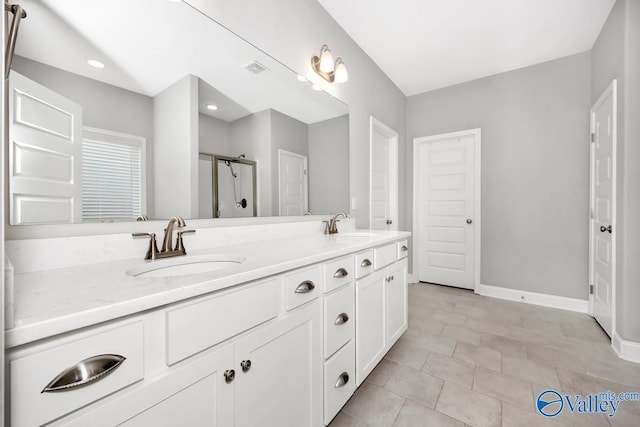 full bath featuring a sink, a shower stall, baseboards, and double vanity