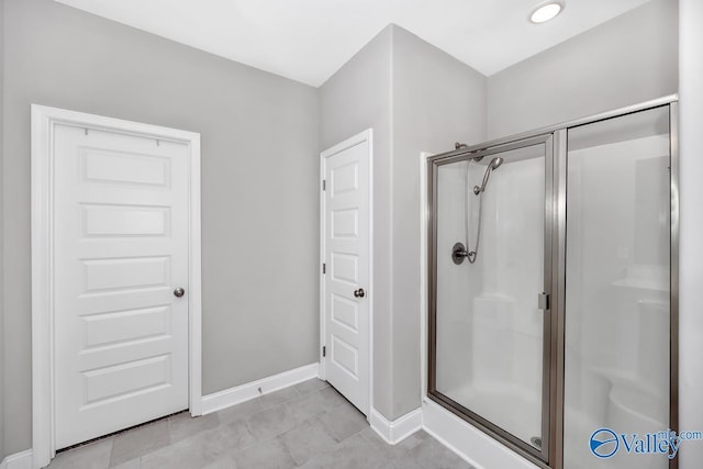 full bathroom with a shower stall and baseboards