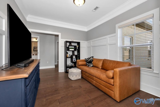 living area featuring visible vents, a decorative wall, ornamental molding, dark wood-type flooring, and baseboards