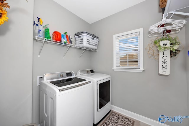 laundry area with laundry area, washing machine and clothes dryer, and baseboards