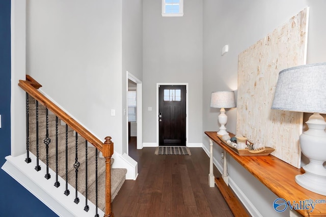 entrance foyer featuring stairs, dark wood finished floors, a towering ceiling, and baseboards