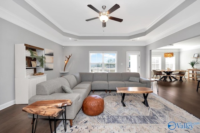 living room featuring ornamental molding, a tray ceiling, and dark wood-style flooring