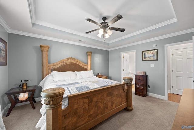 bedroom with crown molding, baseboards, light carpet, and a tray ceiling
