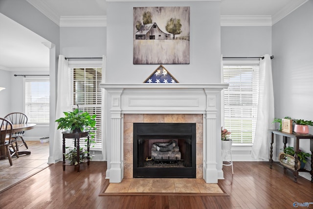 room details featuring ornamental molding, a tile fireplace, and wood finished floors