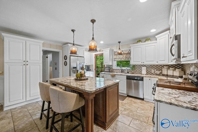 kitchen with light stone counters, tasteful backsplash, appliances with stainless steel finishes, and a kitchen island