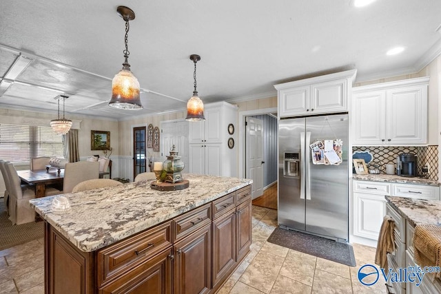 kitchen with hanging light fixtures, white cabinetry, light stone countertops, and stainless steel refrigerator with ice dispenser