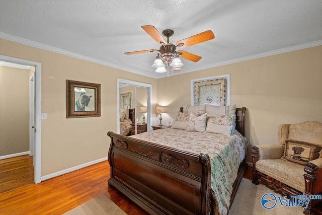 bedroom with a closet, wood finished floors, baseboards, and ornamental molding