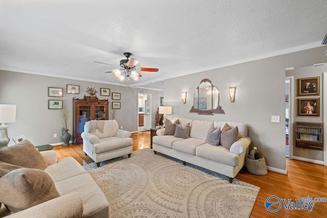 living room featuring a ceiling fan, ornamental molding, heating unit, and wood finished floors