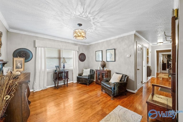 living area featuring a notable chandelier, crown molding, light wood-type flooring, and a textured ceiling