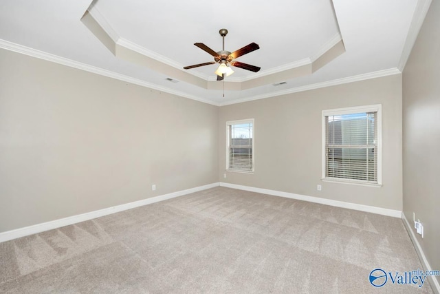 spare room featuring a tray ceiling, light colored carpet, ceiling fan, and baseboards