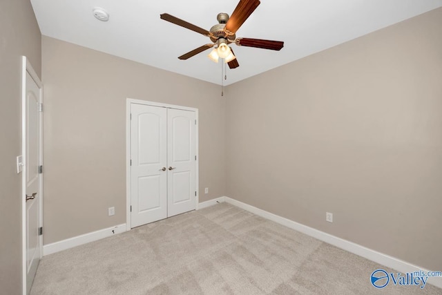 unfurnished bedroom featuring a ceiling fan, baseboards, a closet, and light colored carpet