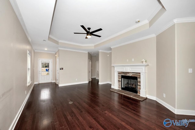 unfurnished living room featuring a fireplace, wood finished floors, a ceiling fan, baseboards, and a tray ceiling