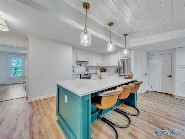 1901 Governors Dr SE, Huntsville, AL 35801 - kitchen featuring stainless steel appliances, crown molding, white cabinets, light wood-style floors, and a center island with sink