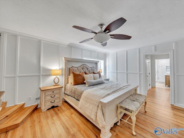 1901 Governors Dr SE, Huntsville, AL 35801 - bedroom featuring a decorative wall, a textured ceiling, light wood-style flooring, and a ceiling fan
