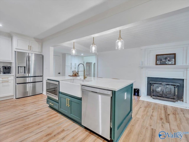 1901 Governors Dr SE, Huntsville, AL 35801 - kitchen featuring stainless steel appliances, green cabinetry, light wood-style floors, white cabinetry, and a fireplace with raised hearth