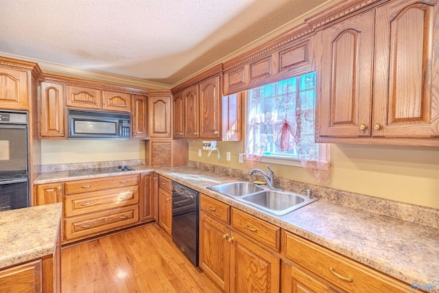 kitchen featuring a sink, black appliances, light countertops, light wood-style floors, and a textured ceiling