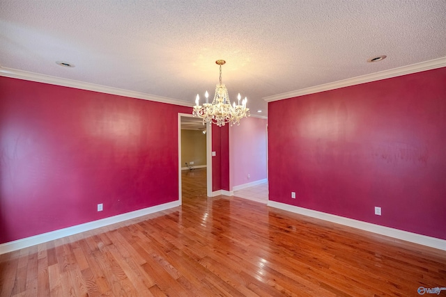 unfurnished room with crown molding, baseboards, a chandelier, wood finished floors, and a textured ceiling