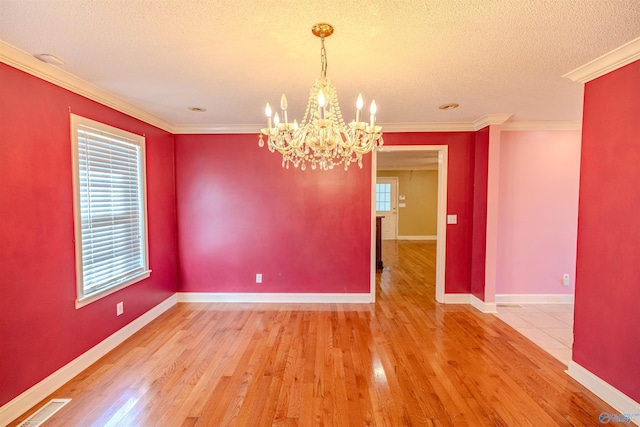 empty room featuring visible vents, a textured ceiling, crown molding, and hardwood / wood-style flooring