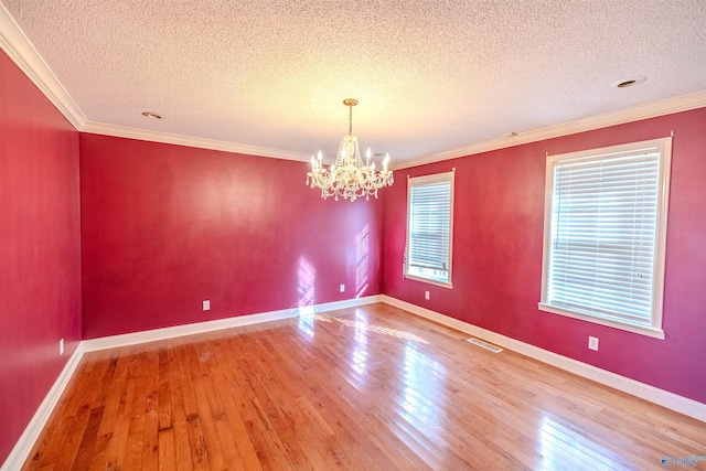 unfurnished room with visible vents, baseboards, a chandelier, ornamental molding, and wood-type flooring