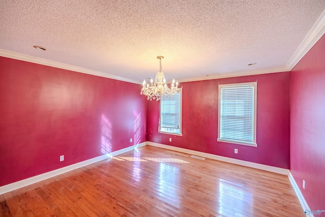 empty room featuring crown molding, an inviting chandelier, and wood finished floors