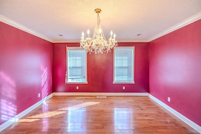 empty room featuring crown molding, baseboards, a chandelier, hardwood / wood-style flooring, and a textured ceiling