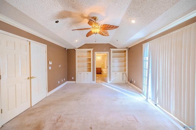 unfurnished bedroom with lofted ceiling, ornamental molding, carpet, and a textured ceiling