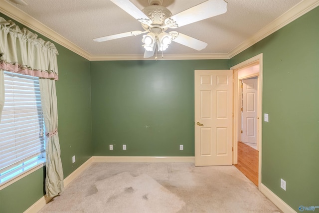 carpeted empty room featuring baseboards, plenty of natural light, and crown molding