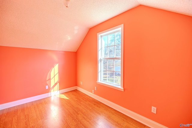 bonus room with plenty of natural light, a textured ceiling, and wood finished floors
