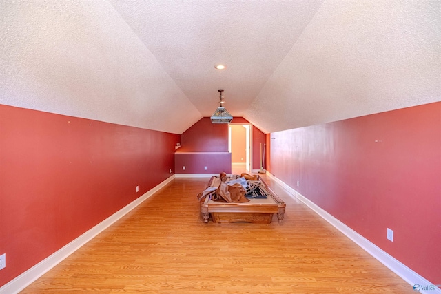 playroom with vaulted ceiling, wood finished floors, baseboards, and a textured ceiling