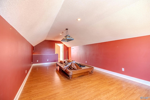 home theater featuring baseboards, a textured ceiling, lofted ceiling, and wood finished floors