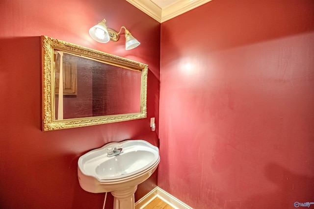 bathroom with ornamental molding, baseboards, and a sink