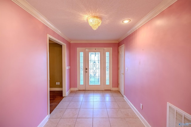 foyer entrance with light tile patterned flooring, visible vents, a textured ceiling, and ornamental molding