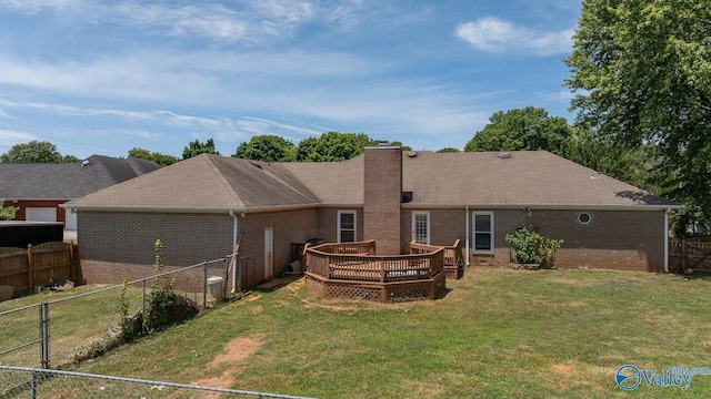 back of property featuring a lawn, a chimney, brick siding, a deck, and a fenced backyard
