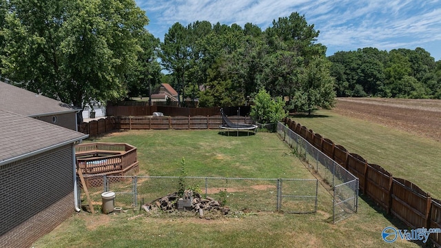 view of yard featuring a trampoline, a gate, and a fenced backyard